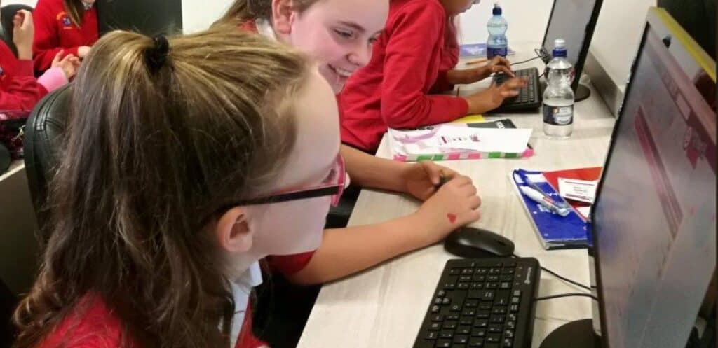 Students smiling in a classroom, while looking at a monitor with an I'm a Medic live chat happening